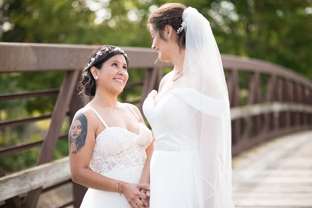 Brides looking at each other while standing on bridge