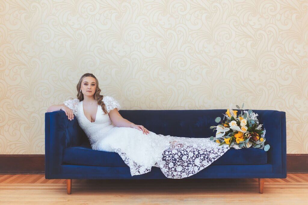 Bride lounging on blue velvet sofa at The Haight