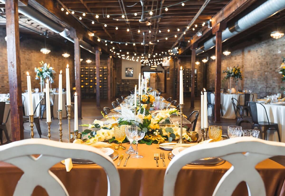 Head table with gold table cloth and yellow and white flowers at loft wedding venue Chicago