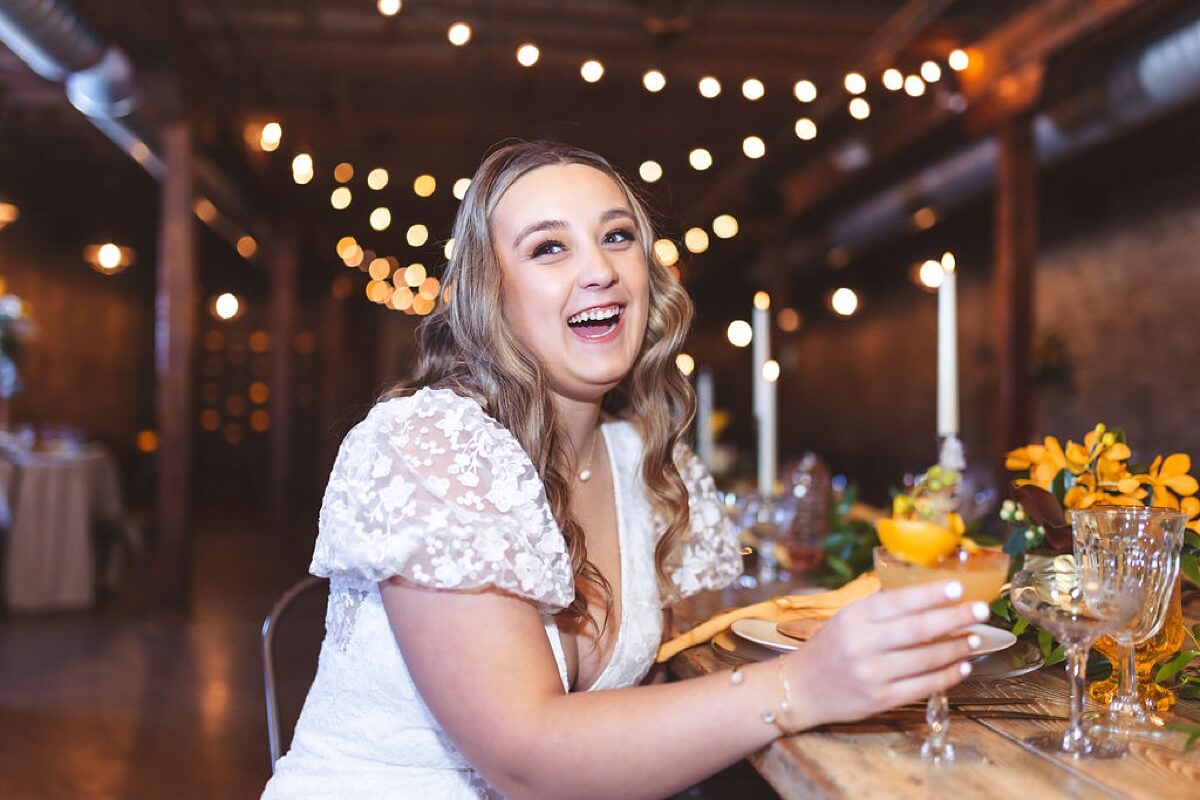 Bride laughing while holding cocktail at loft wedding venue Chicago