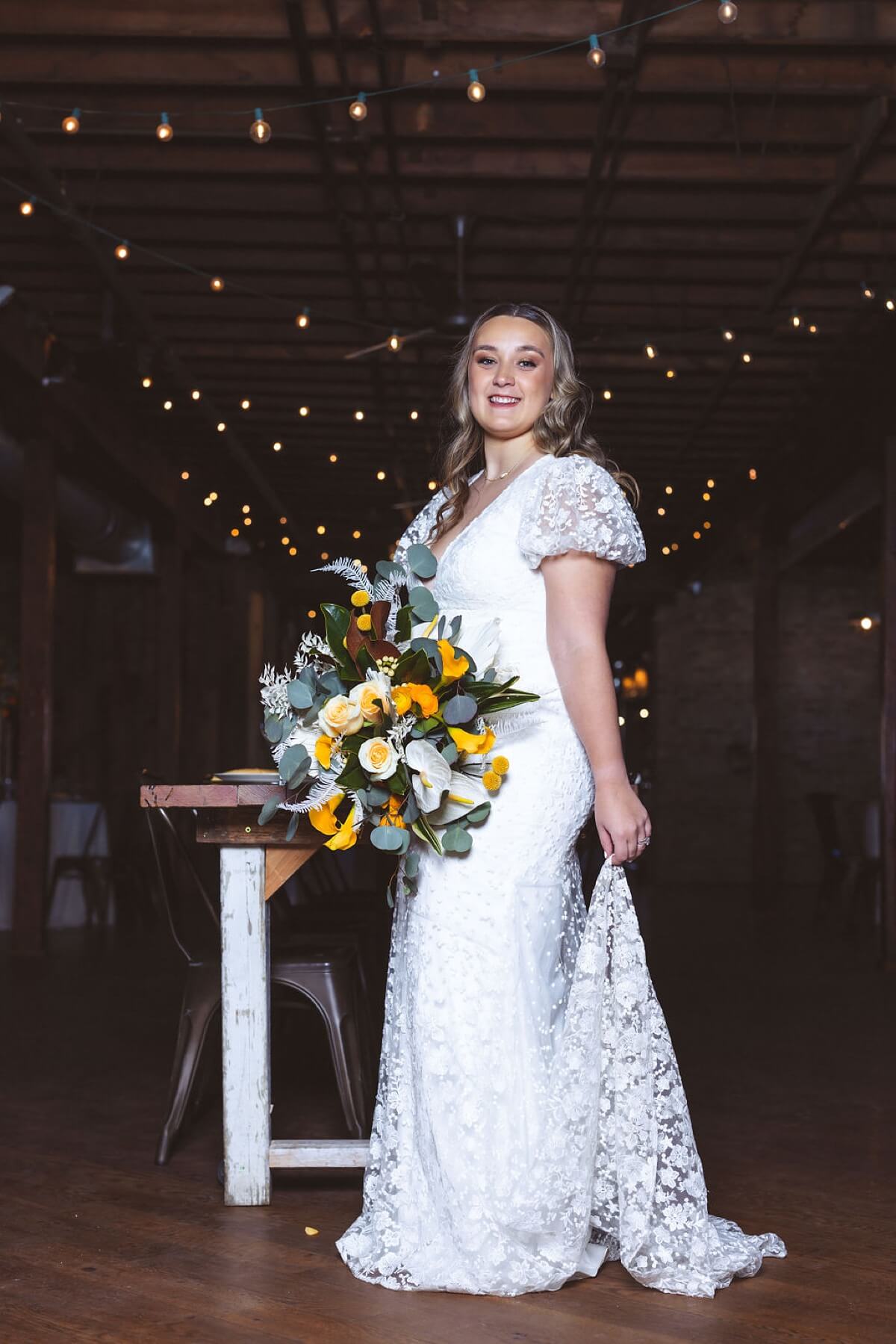 Bride wearing puffed sleeve wedding gown holding yellow and white bouquet at loft wedding venue Chicago