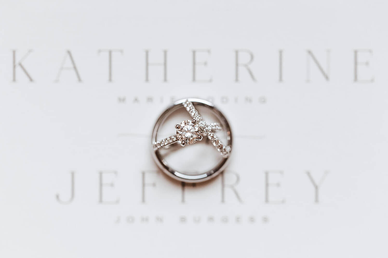 Platinum wedding rings and engagement band on wedding invitation