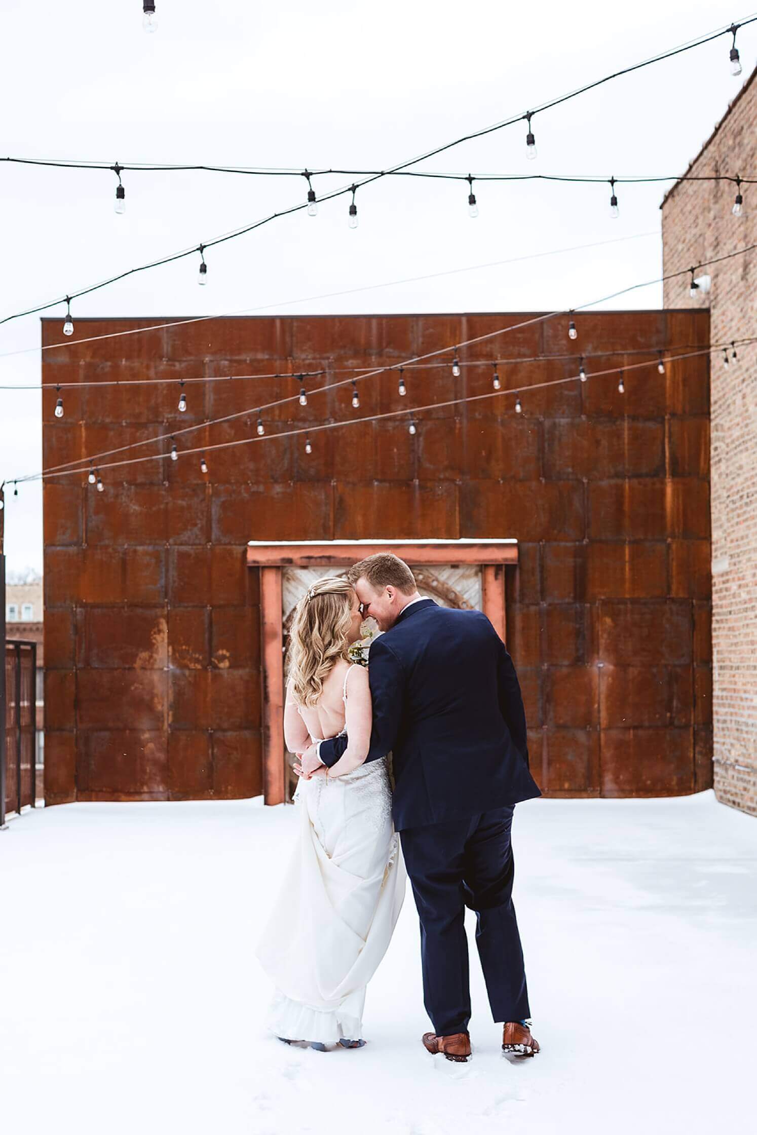 Bride and groom kissing in the snow at winter wedding venue