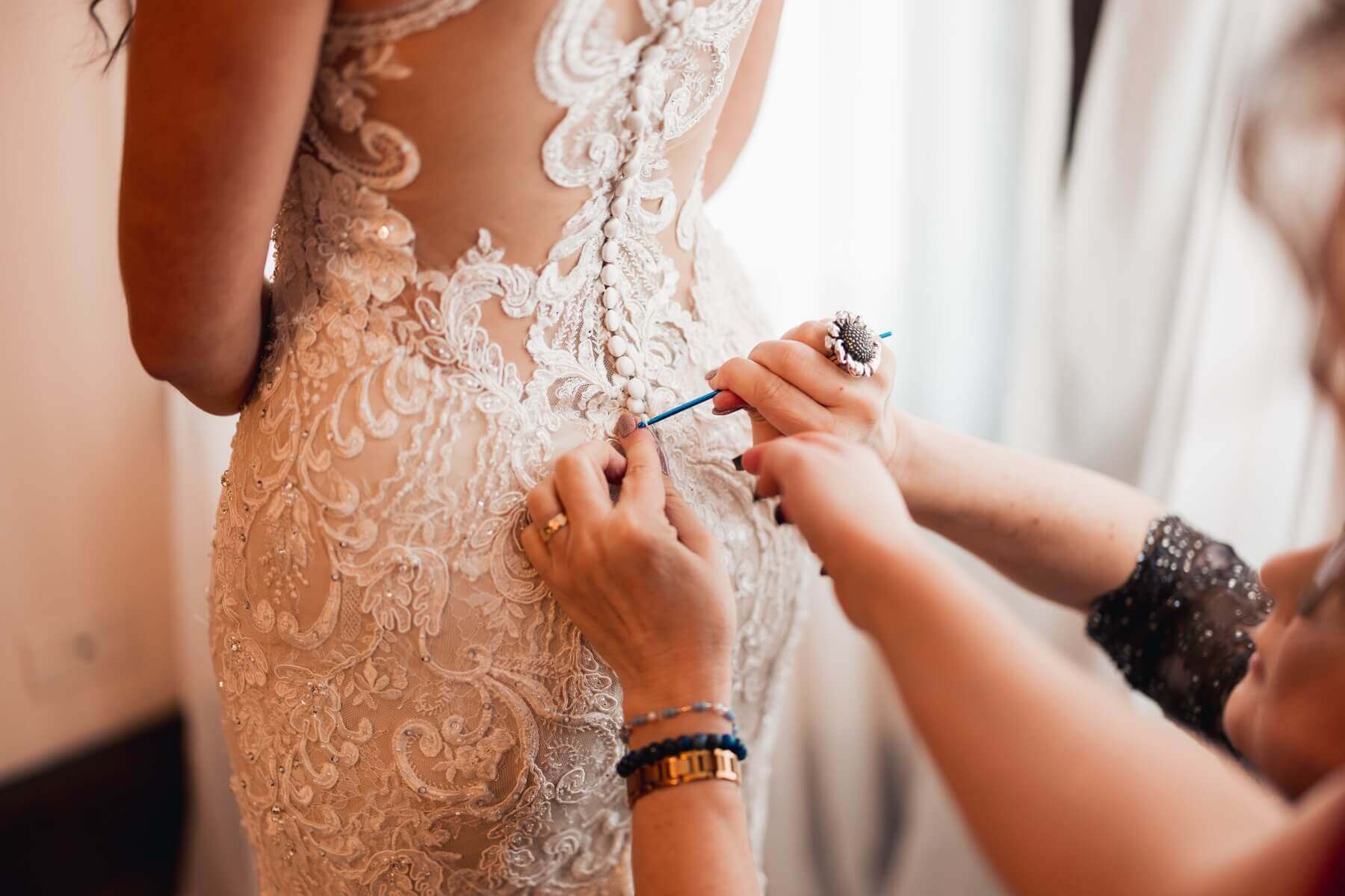 Mom helping button up bride's dress