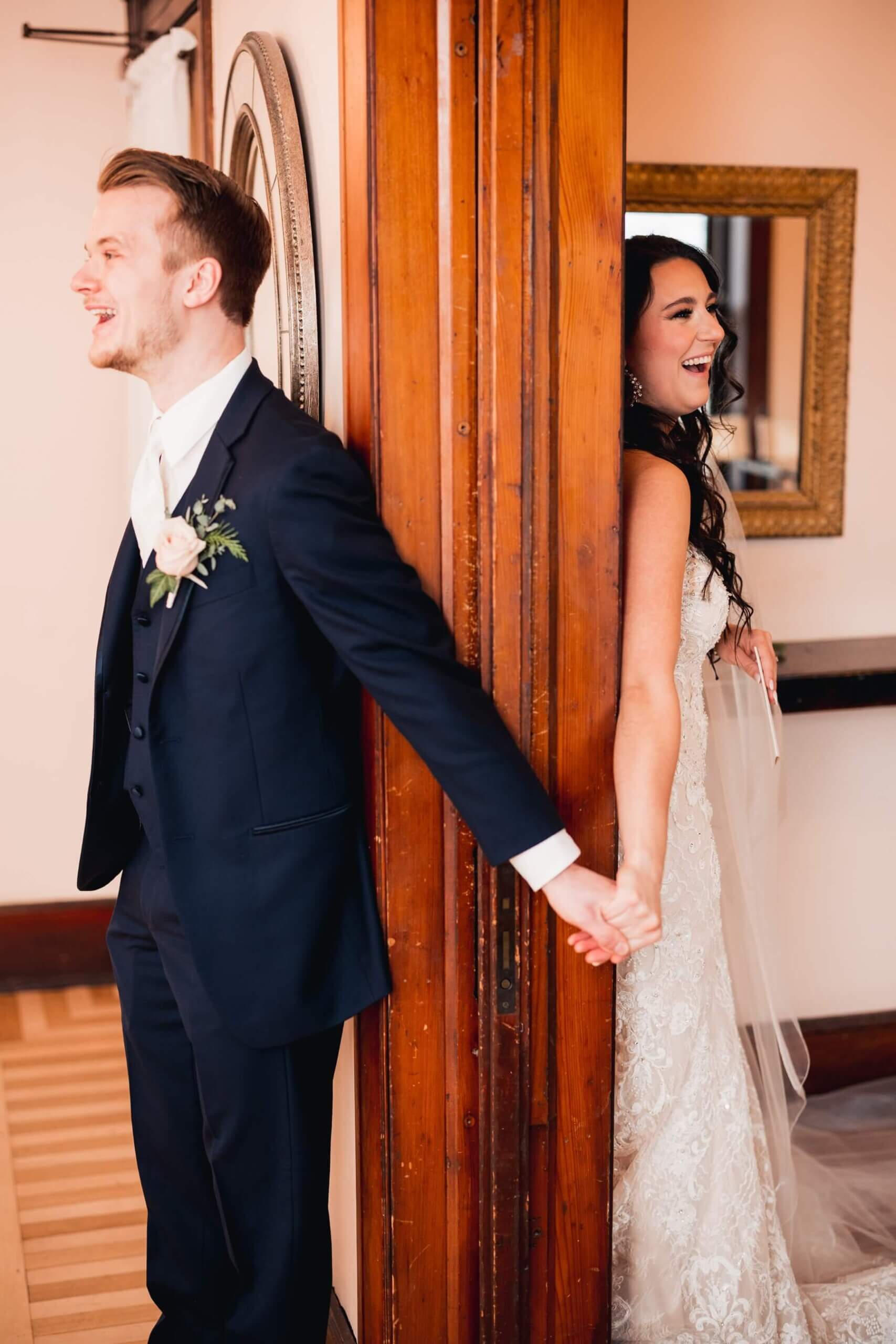 Bride and groom holding hands around wall at wedding venue in Illinois
