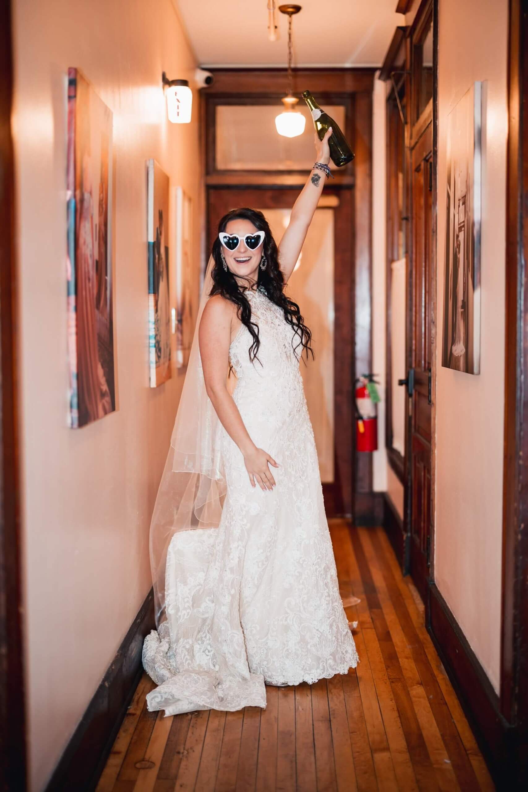 Bride wearing heart sunglasses holding bottle of champagne