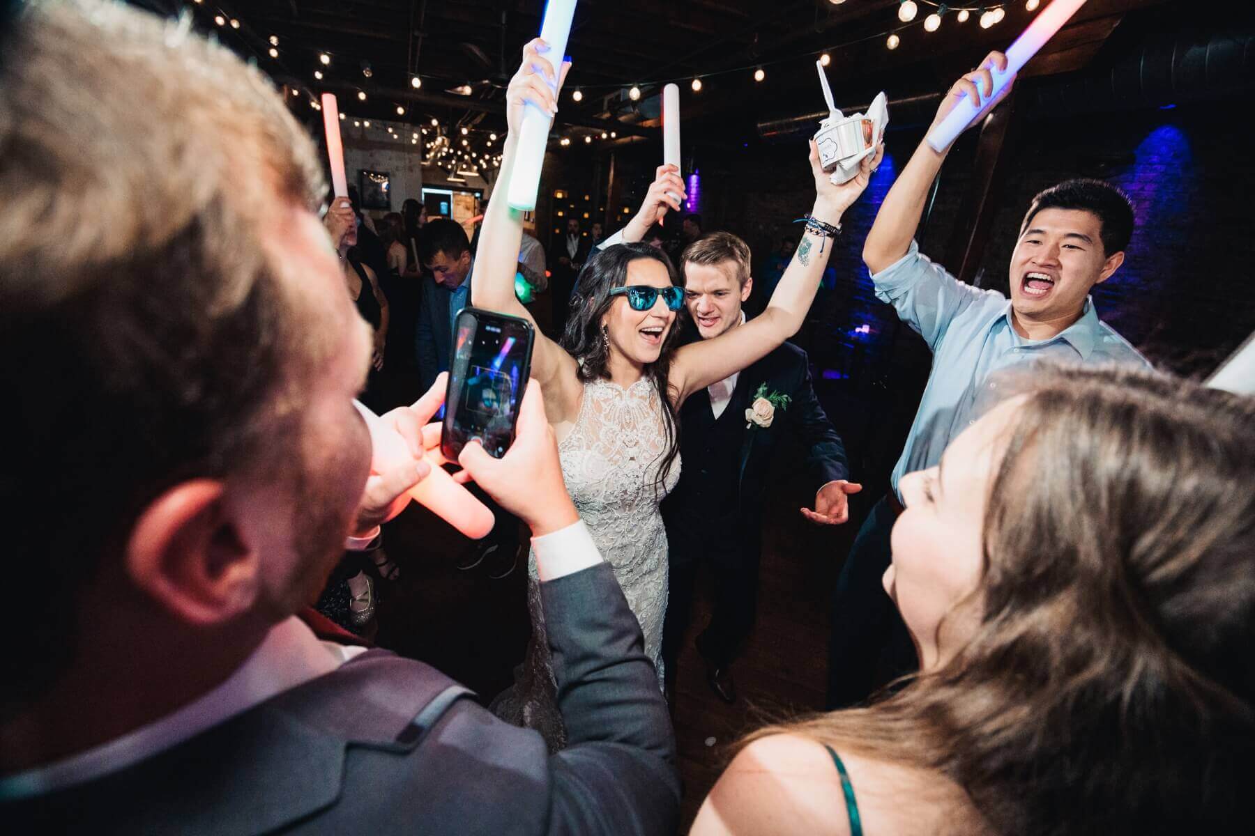 Bride dancing with sunglasses and foam glow sticks