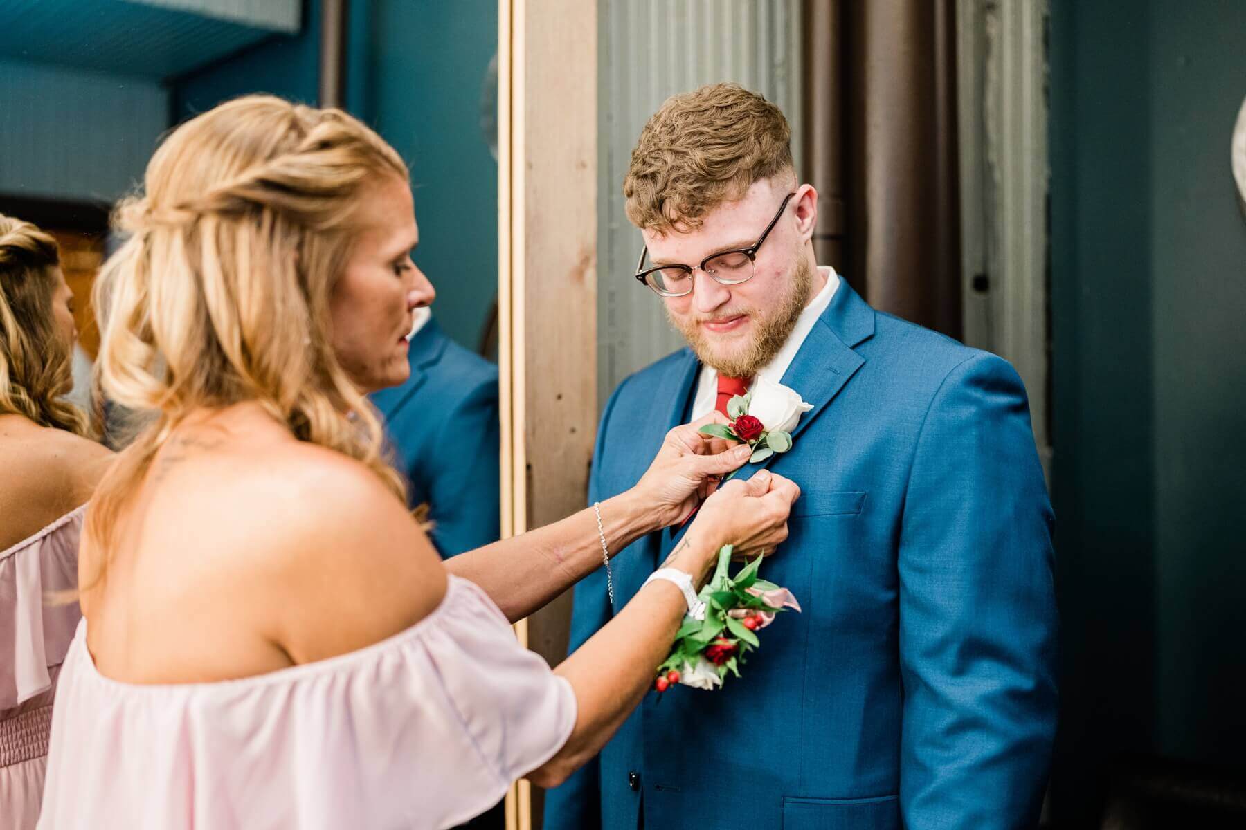 Mother of groom helping groom with his boutonniere