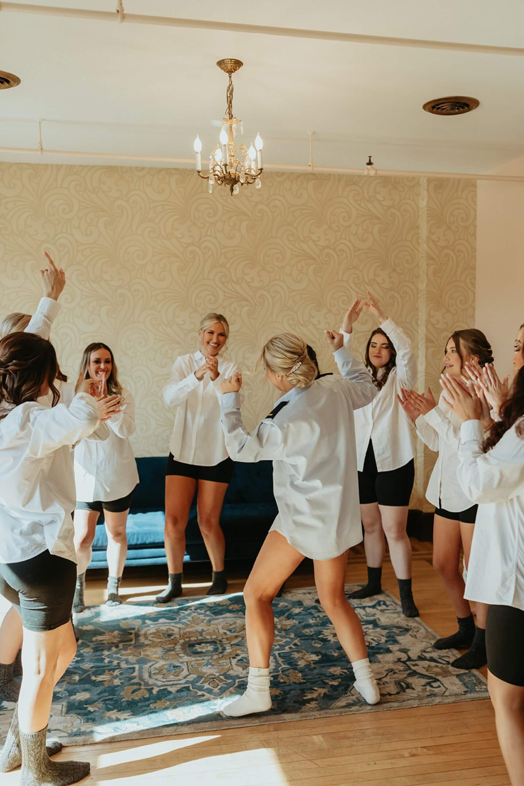 Bride dancing in oversized shirt with bridesmaids