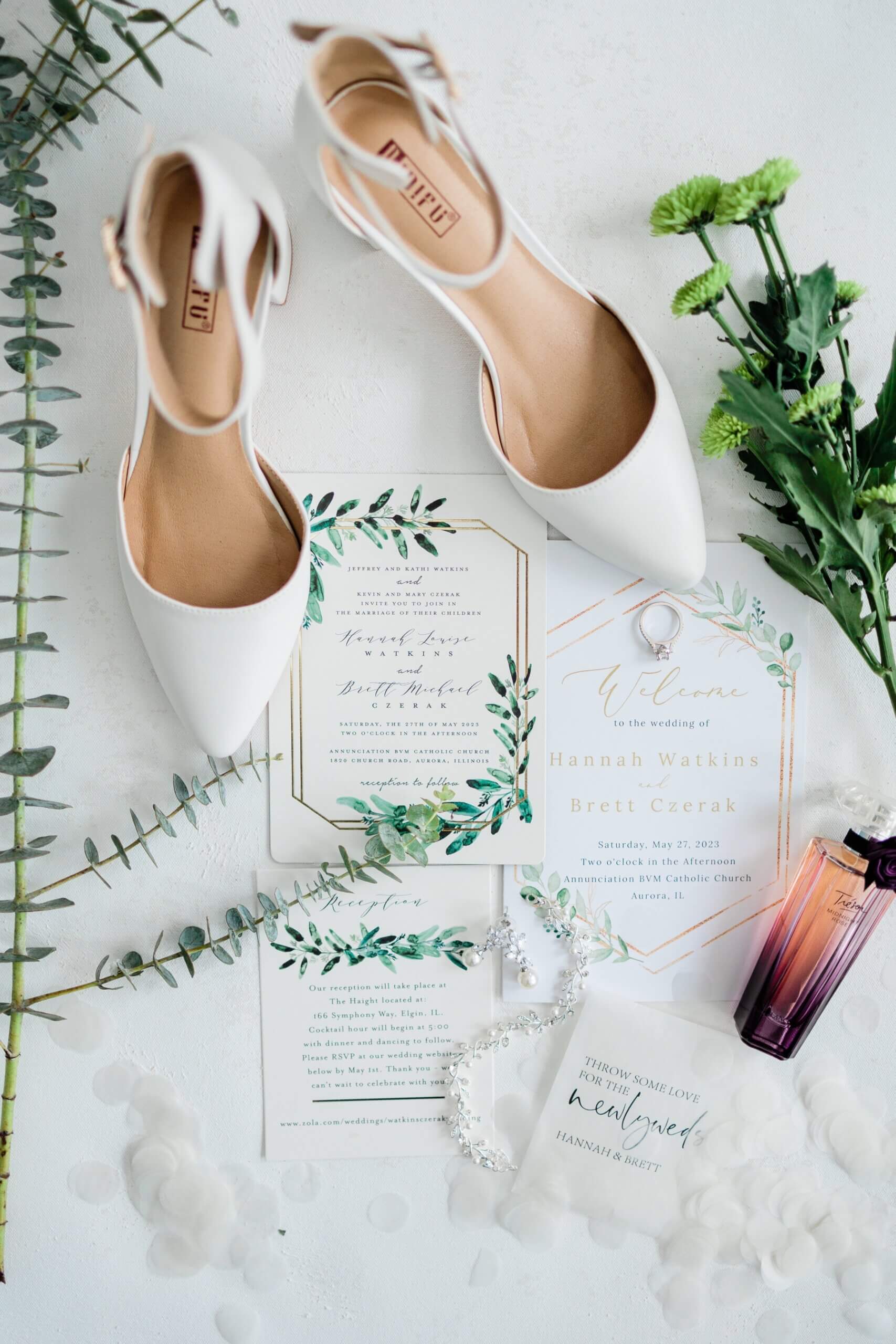 White wedding invitation with white shoes and greenery