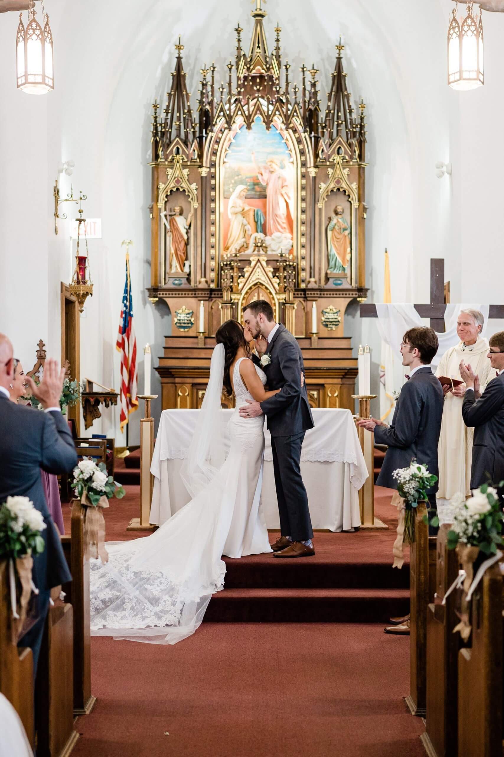 Bride and groom kissing in Catholic ceremony