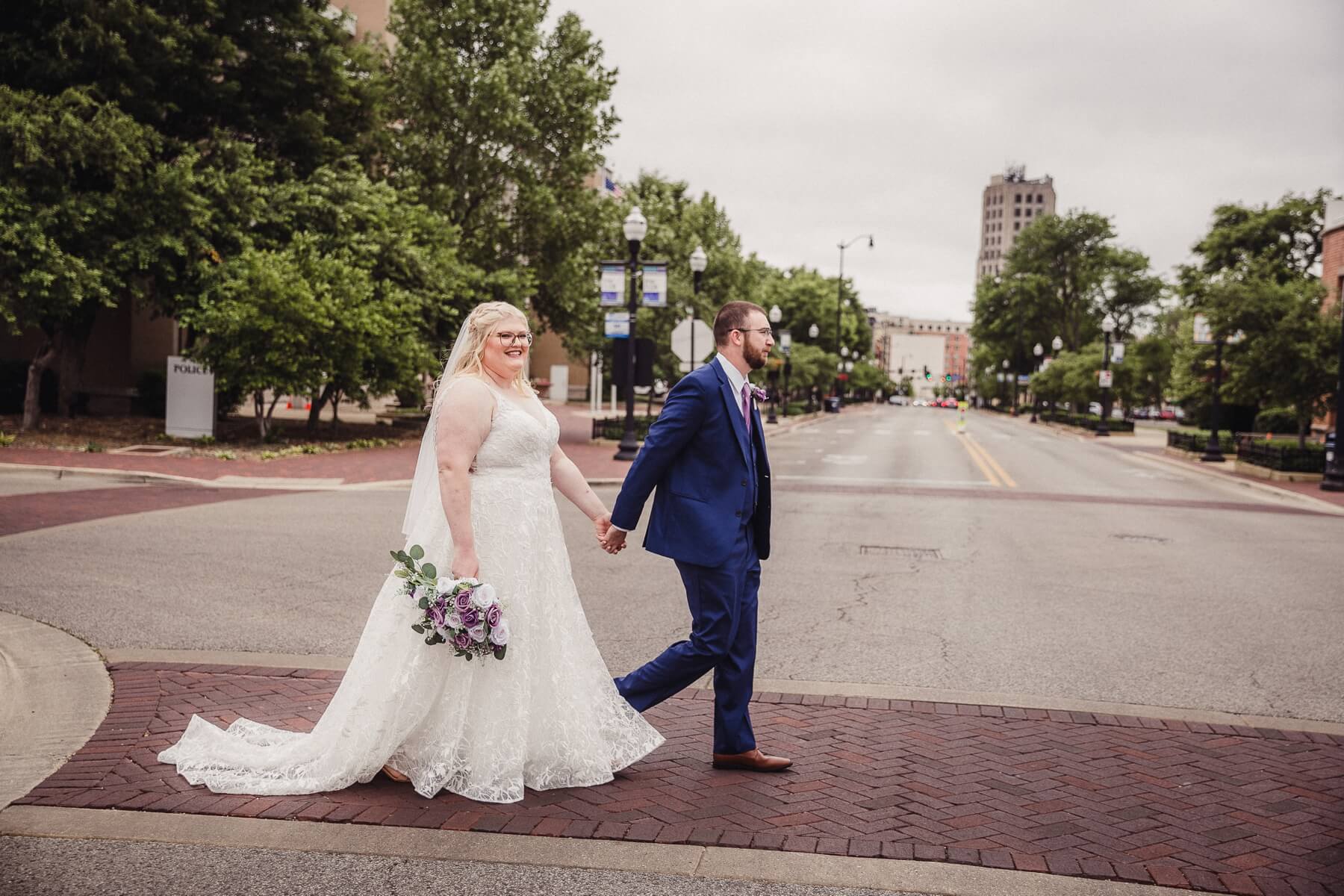 Bride and groom holding hands and walking in the street
