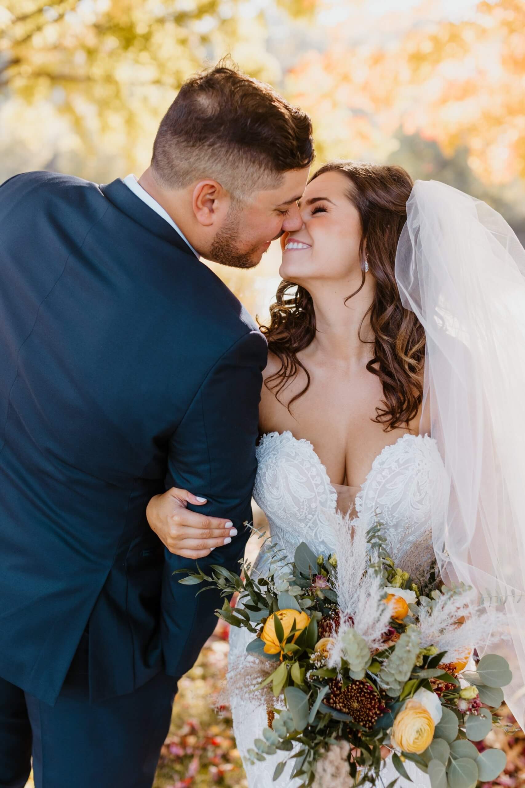 Bridge holding boho bouquet while standing next to groom and kissing him