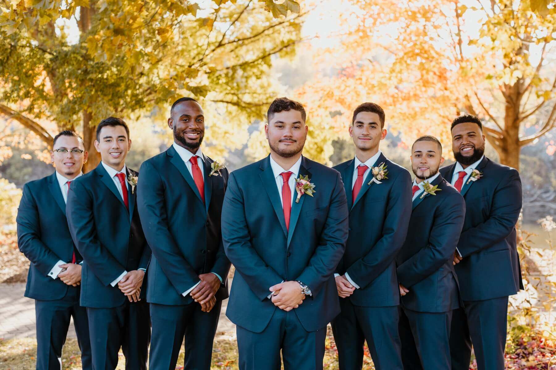 Groom with groomsmen in navy blue suits with red ties