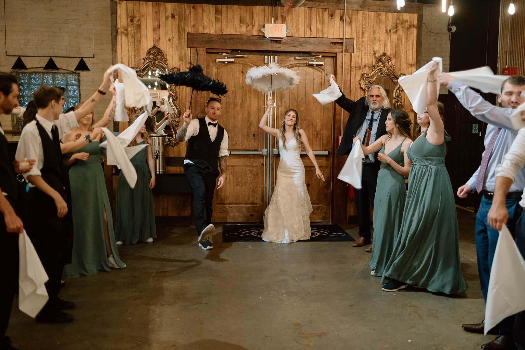 Bride and groom holding umbrellas while guests wave napkins during second line send-off